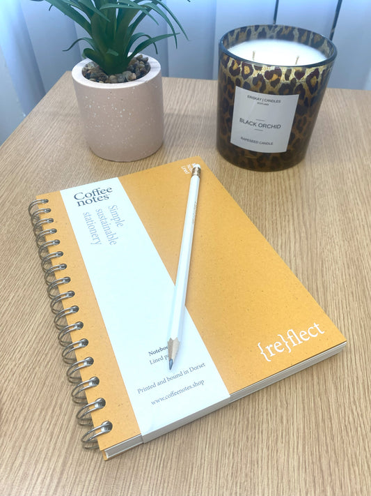 Recycled yellow note book on desk with pencil